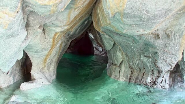 Sunlight filters through the Marble Caves, near Chile Chico, Chile. Aqua water of Lago General Carrera reflects on the patterned stone in the morning.