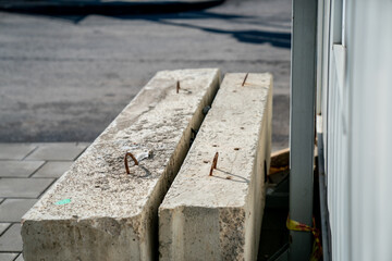 Heavy concrete blocks with exposed metal reinforcements placed at roadside construction site for urban barrier or foundation work