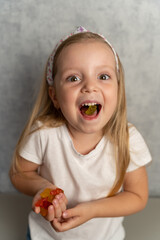 Portrait of a cheerful little girl eating gummy vitamins in the shape of bears. Multivitamins or...