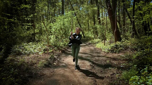 Terrified woman swinging stick to protect from serial killer in forest. Frightened female attacking maniac with branch on woodland path. Panicked lady defending with tree limb from murderer in wooded