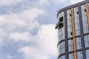 The corner of a modern high-rise building features a glass facade. Soft lighting and a cloudy sky emphasize the industrial feel of urban architecture.
