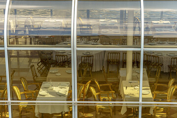The restaurant is located behind a glass partition with tables set. The combination of natural and architectural elements adds elegance and visual depth to the space.