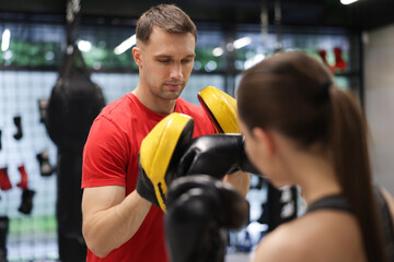 Young woman exercising with professional personal trainer in gym