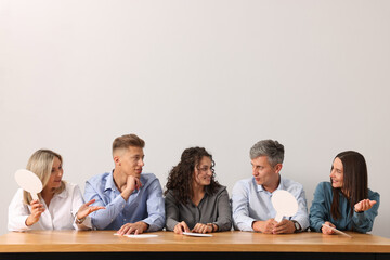 Panel of judges consulting at table against light grey background
