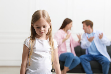 Upset little girl and her parents fighting at home, selective focus