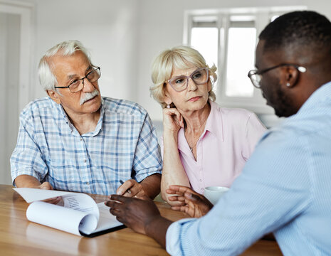 Happy senior old family couple clients make financial insurance estate business deal contract signing, agent lawyer, satisfied mature customers signing contract meeting bank manager agree on investmen