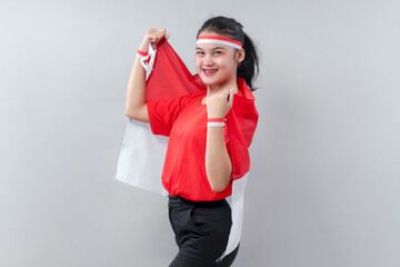 Confident Indonesian woman proudly poses with the red and white flag, wearing patriotic...