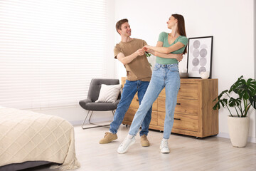 Happy young couple dancing together at home