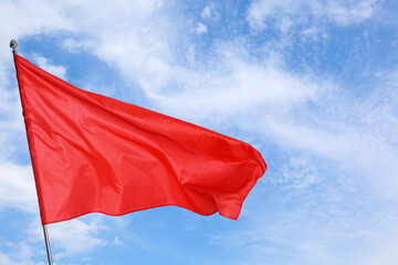 Red flag waving against blue sky outdoors