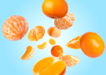 Juicy tangerines swirling in air against light blue gradient background
