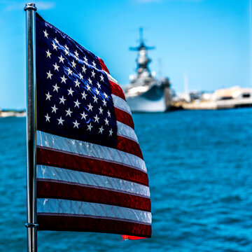 American flag blowing in the wind with navy ship in the background, Hawaii, USA