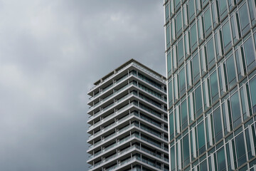 Contemporary high-rise building with numerous glass windows and balconies, gray sky background, urban architecture, clean lines and geometric shapes.


