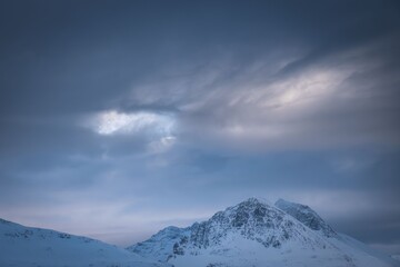 Snowy mountains under a dramatic sky at dusk.