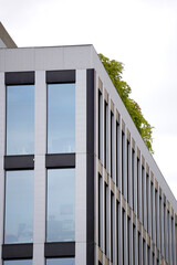 Modern office building corner with large glass windows reflecting sky, vertical black and white...