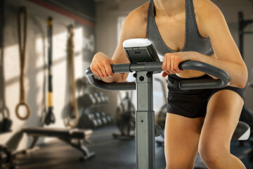 Young woman working out on a stationary exercise bike in a modern gym. 