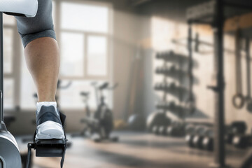Close up of young woman working out on a stationary exercise bike in a modern gym. 