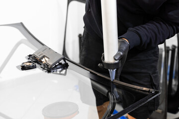 Urethane caulking gun applies flexible adhesive, forming a watertight seal at car windshield...