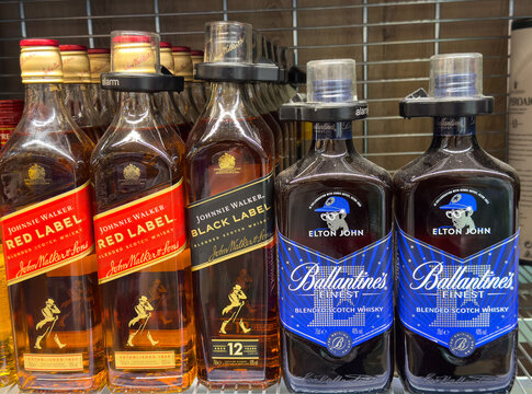 Villach, Austria - July 24, 2025: Johnnie Walker Red Label and Black Label alongside Elton John Ballantine's Finest whisky bottles on a retail shelf, showcasing premium spirits selection
