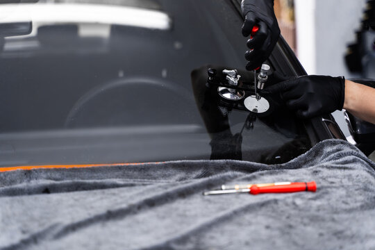 Resin repair on windshield using injector application to restore structural clarity. Windshield crack repair using resin injection. Technician using windshield injector tool to fix bullseye crack.