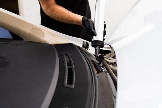 Applying adhesive to a car windshield using a caulking gun. Urethane caulking gun applies flexible adhesive, forming a watertight seal at car windshield replacement.