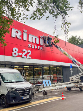 Riga, Latvia - July 24, 2025: Workers installing large illuminated sign on Rimi supermarket building, showcasing modern retail architecture and branding in urban environment