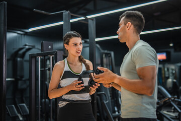 Personal trainer discuss with his female client about goals at gym