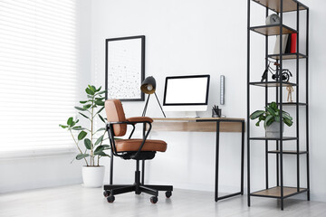 Fototapeta premium Stylish workplace with wooden desk, lamp and computer indoors. Mockup for design
