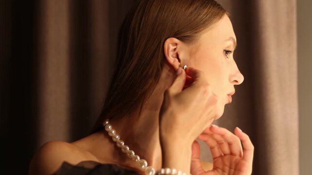 Woman wearing beautiful earring while getting ready near mirror indoors, camera moving up