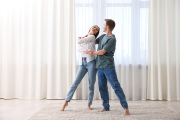 Happy young couple dancing together at home