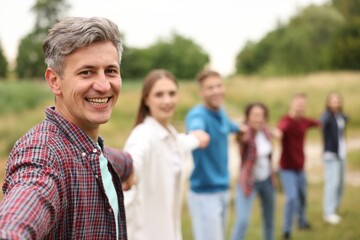 Team building. Group of happy people holding hands outdoors, selective focus