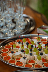 Elegant catering platter with gourmet appetizers: red caviar tartlets, brie cheese cubes topped with grapes and blueberries on skewers. Perfect for event, party, or luxury food stock content.
