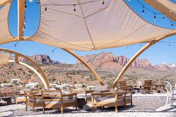 Outdoor canopy lounge with shade sails and wooden furniture sits against a scenic desert backdrop in southern Utah, blending luxury with rugged surroundings