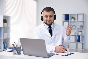 Obraz premium Doctor in headphones having online consultation via laptop indoors