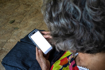 unidentifiable elderly woman fiddles with her mobile phone with blank screen mockup in brazil