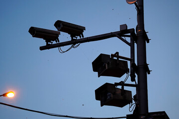 Surveillance cameras mounted on metal pole, dusk lighting, spider webs visible on equipment,...