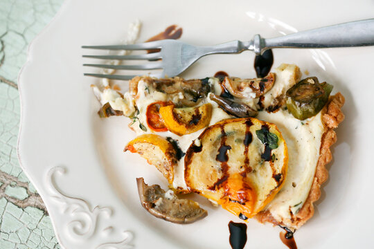 A rustic slice of grilled vegetable tart topped with zucchini, tomatoes, and mushrooms, drizzled with balsamic glaze. Perfect for vegetarian recipes, farmers market promotions, and healthy eating visu