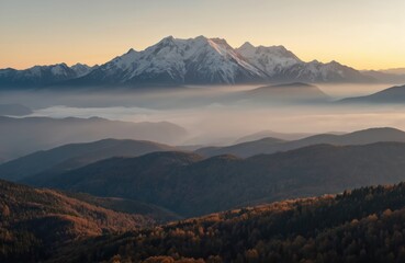 Fototapeta premium Majestic mountain range with snow-capped peaks at sunset. Layers of mist and hills create depth in this landscape. Warm golden light illuminates the scene, perfect for travel and nature themes.