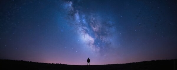 Silhouette of person standing on hill, gazing at vast night sky illuminated by stars and Milky Way. This celestial view evokes wonder and tranquility, highlighting grandeur of universe.