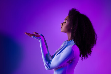 Stylish young woman in a cosmic jumpsuit posing under neon ultraviolet light in a modern artistic...