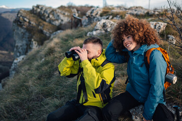 Hikers observing nature with binoculars on mountain top
