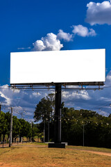 Mockup of the blank billboard under a bright blue sky with white clouds. Outdoor advertising space ready for a message. Simple and clean composition in Brazil