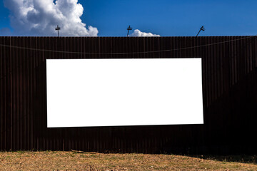 Billboard with a blank screen in steel wall background, on a sunny day. Versatile space for editing...