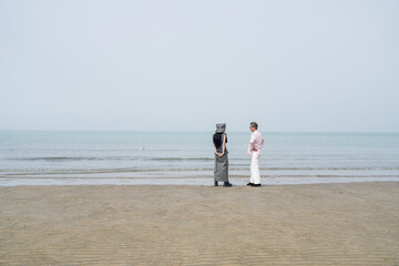 In June 2025, a Korean man and woman in their late fifties walk along the peaceful seashore, enjoying the soft ocean breeze, quiet moments, and each other's company in Incheon Metropolitan City.
