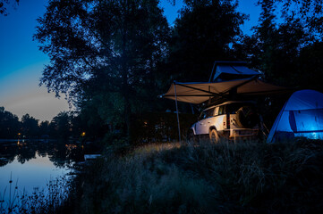 Romantic Camping at the lake with 4x4 Offroad vehicle with roof tent at night