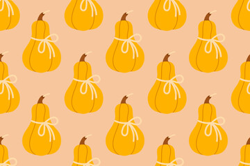 Seamless pattern with orange pumpkins candle tied with bows on soft orange background