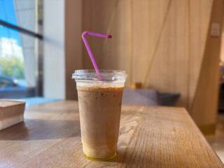 A refreshing iced coffee with a purple straw, sitting on a wooden table with a cozy ambiance.