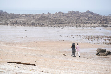 In June 2025, a Korean man and woman in their late fifties walk along the peaceful seashore,...