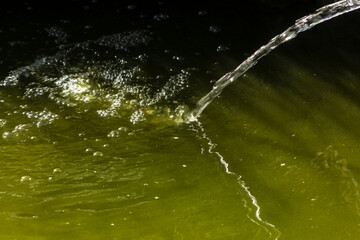 Crystal clear water jet against a dark, rocky background. Illustrates water purity and strength, an...
