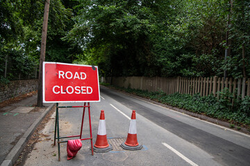 Red "Road Closed" sign positioned by the roadside. UK traffic signage used for roadworks, emergencies, or closures. Clear, bold text in a natural outdoor or urban setting.