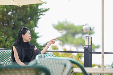 At a seaside cafe terrace in Incheon, South Korea, a Korean woman in her late 50s offers a bite of...